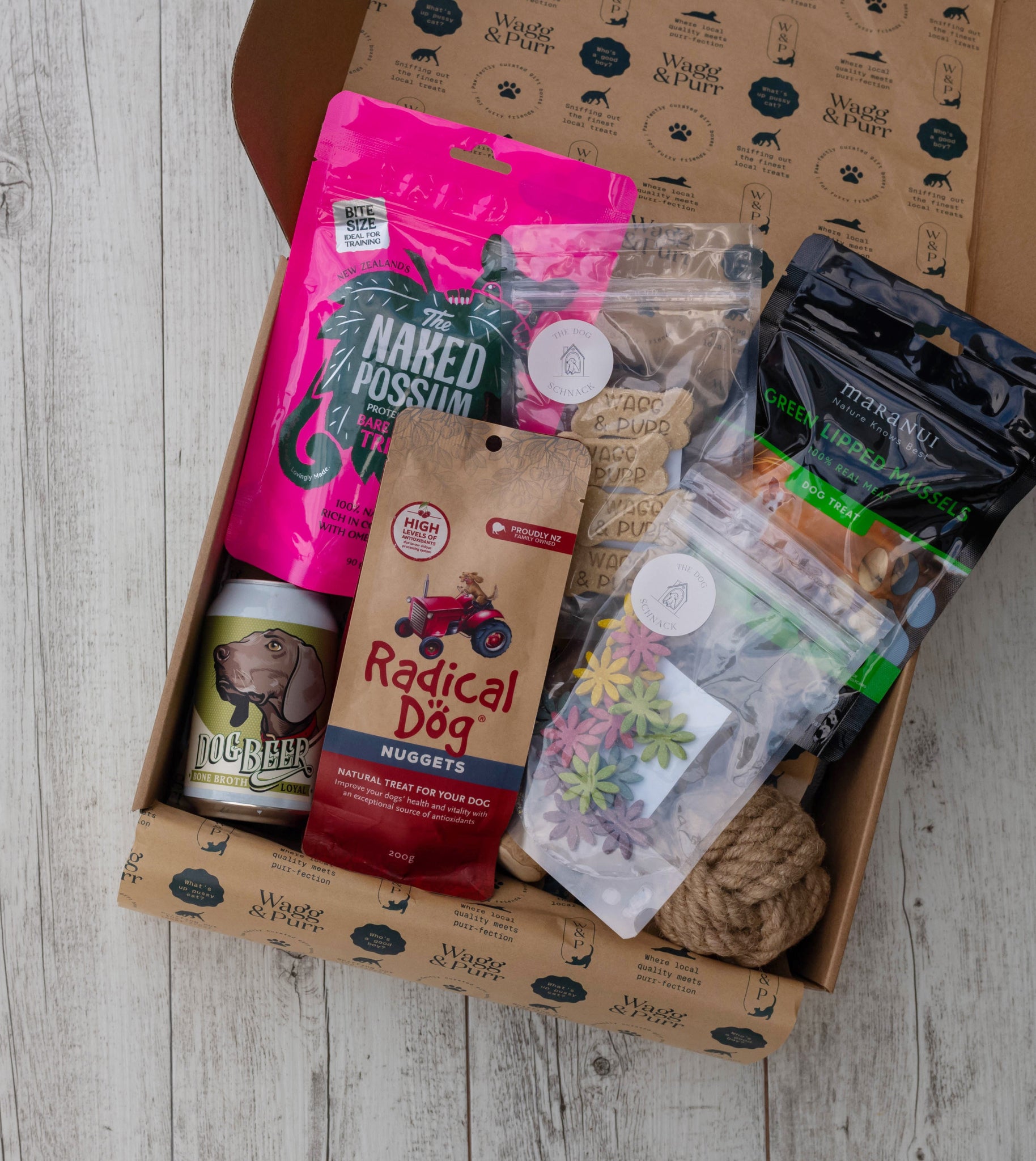 Dog treat and product box with various items on a wooden surface