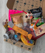 Dog-themed gift box with various items including treats and toys on a wooden surface.