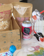 Dog-themed products including cookies, popcorn, and a can with a pug design on a table.